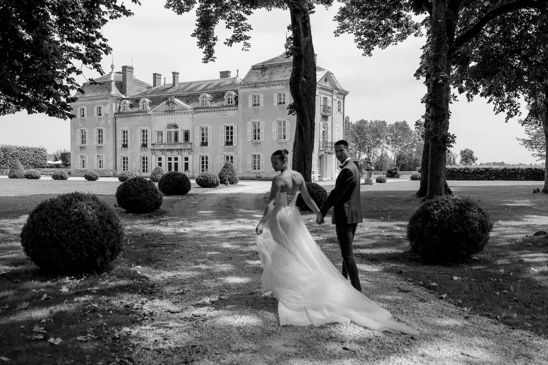 Schwarz-Weiß Hochzeitsfotografie am Chateau de Varennes mit Brautpaar im Park und Schlossfassade